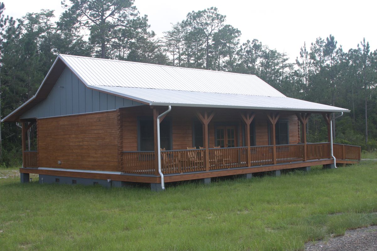 A small wood-sided cabin with a metal roof and front porch