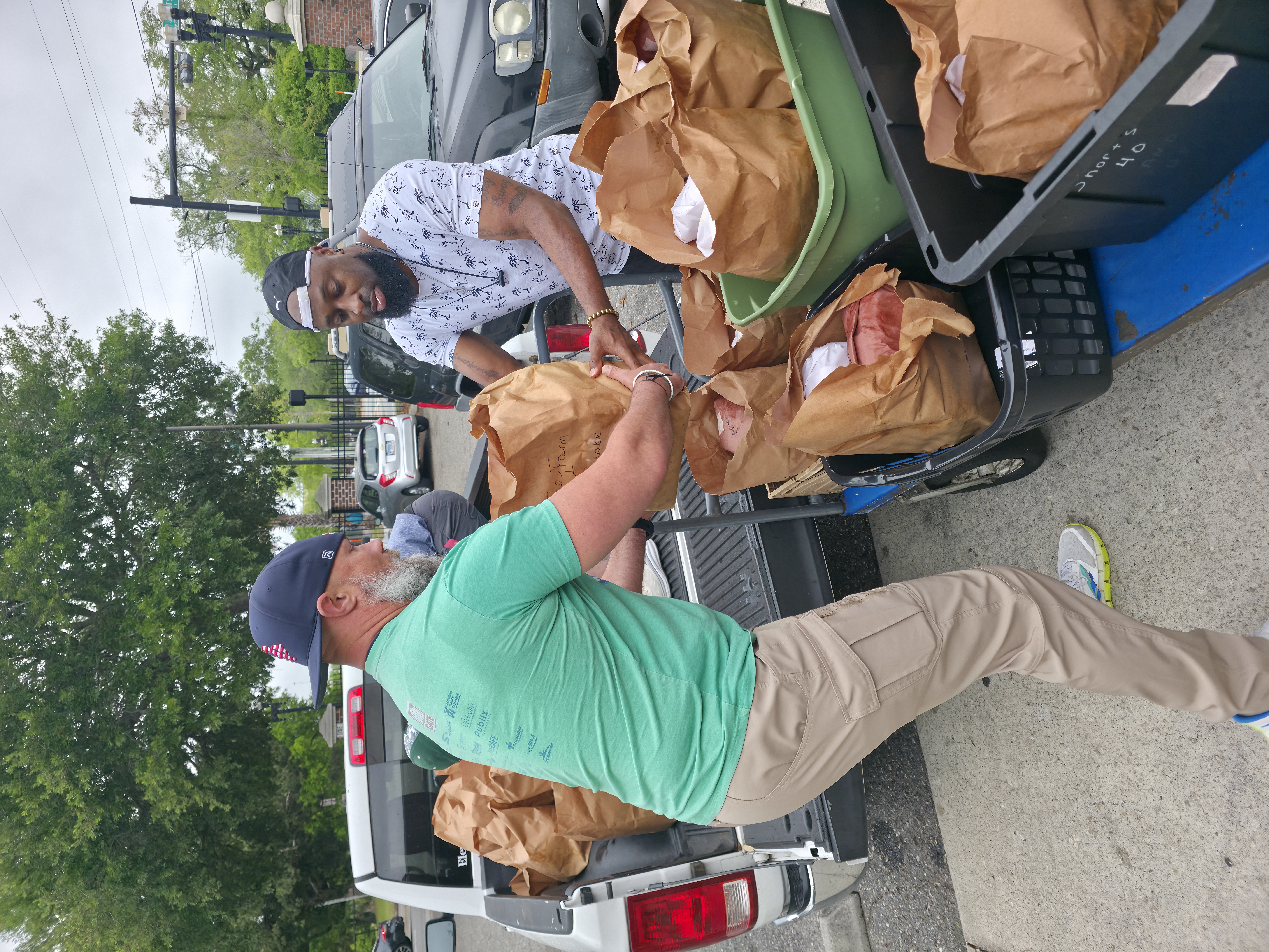 Volunteers unloading bags of food from a pickup truck